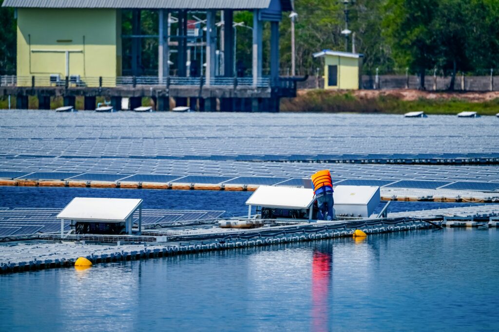 Local worker working at floating solar panels platform on the water of solar cell power plant.