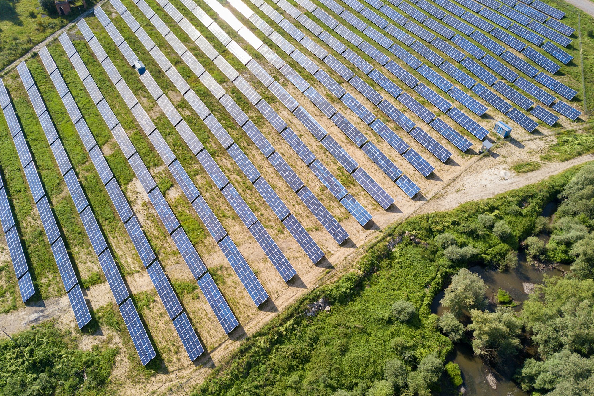 Aerial view of solar power plant on green field. Electric farm with panels for producing clean